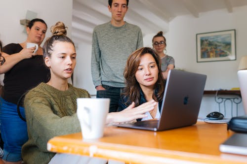 女人在一群人使用macbook的绿色上衣