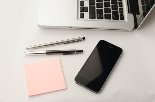 两只可伸缩笔和macbook旁边的太空灰iphone 6